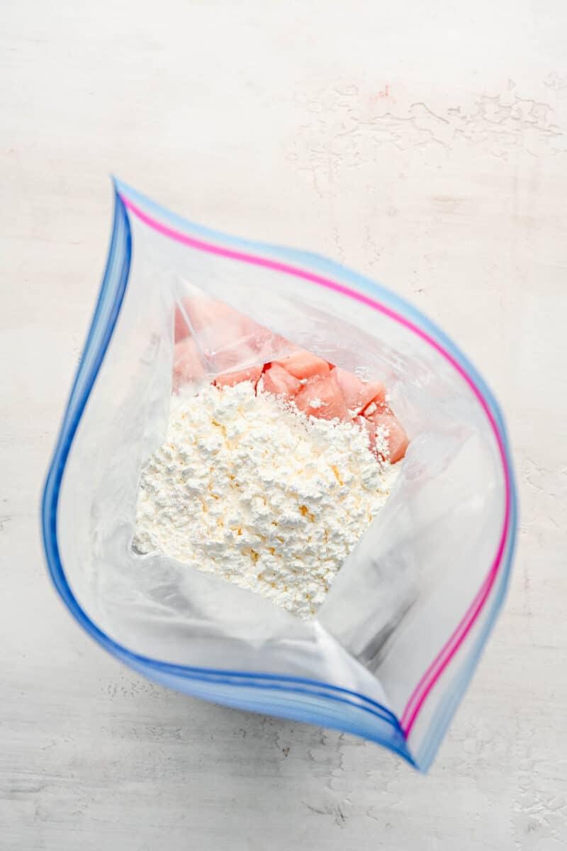 Chicken pieces and cornstarch combined in a zip-top bag.