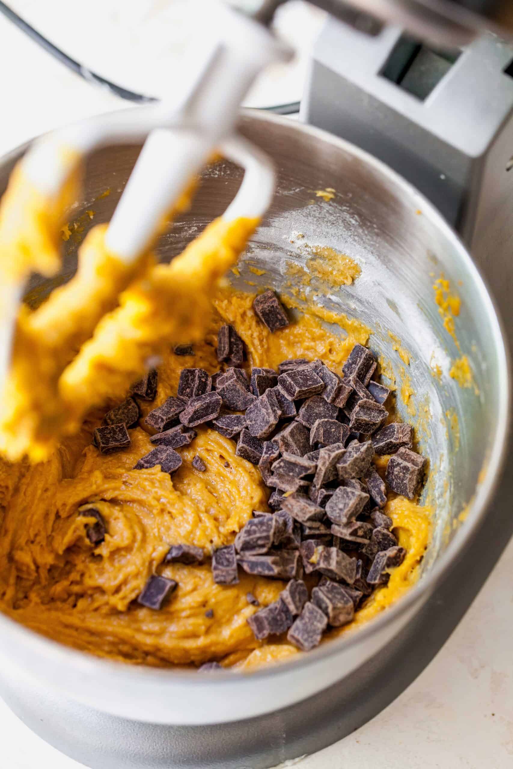 Chocolate chunks added to pumpkin muffin batter in a stand mixer.