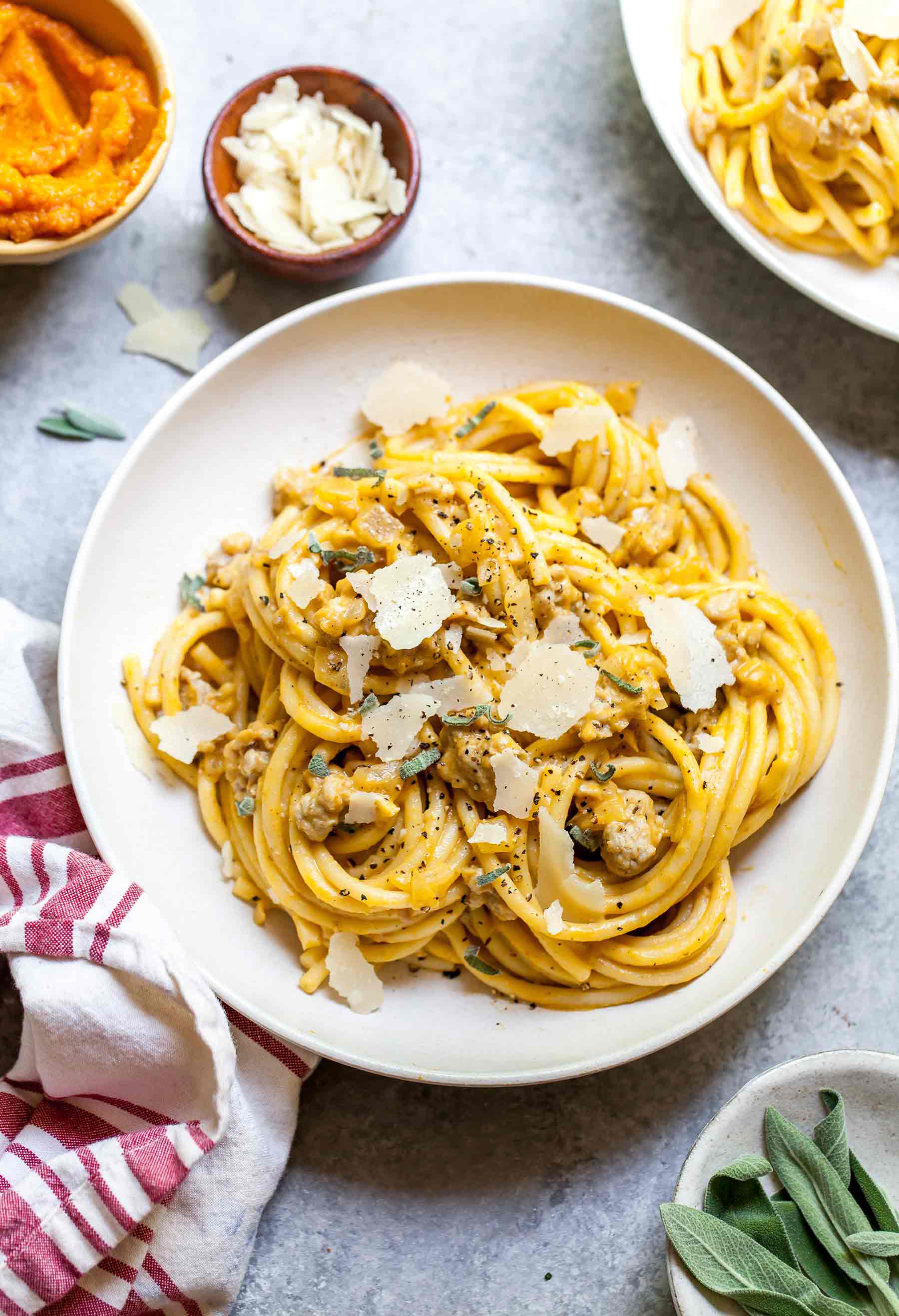 Overhead shot of creamy pumpkin pasta with chicken sausage in white bowl