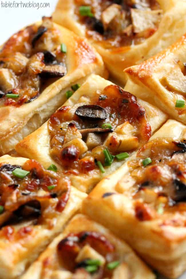 Closeup shot of Caramelized Onion, Mushroom, Apple, and Gruyere Puff Pastry Appetizers garnished with fresh chives