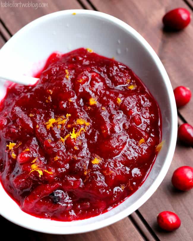 Overhead shot of Cranberry Orange Sauce in white bowl with cranberries scattered in background