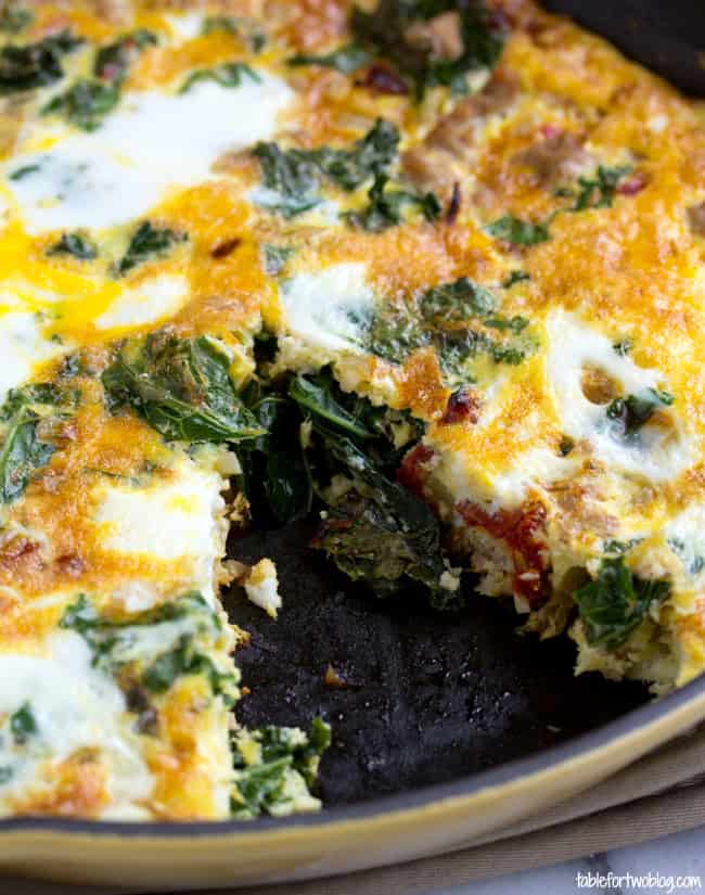 Close up of a turkey and vegetable frittata in a cast iron skillet with a slice missing.