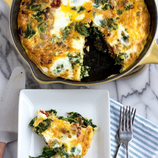 Overhead view of a slice of turkey and vegetable frittata on a square plate, next to a full frittata in a cast iron skillet.