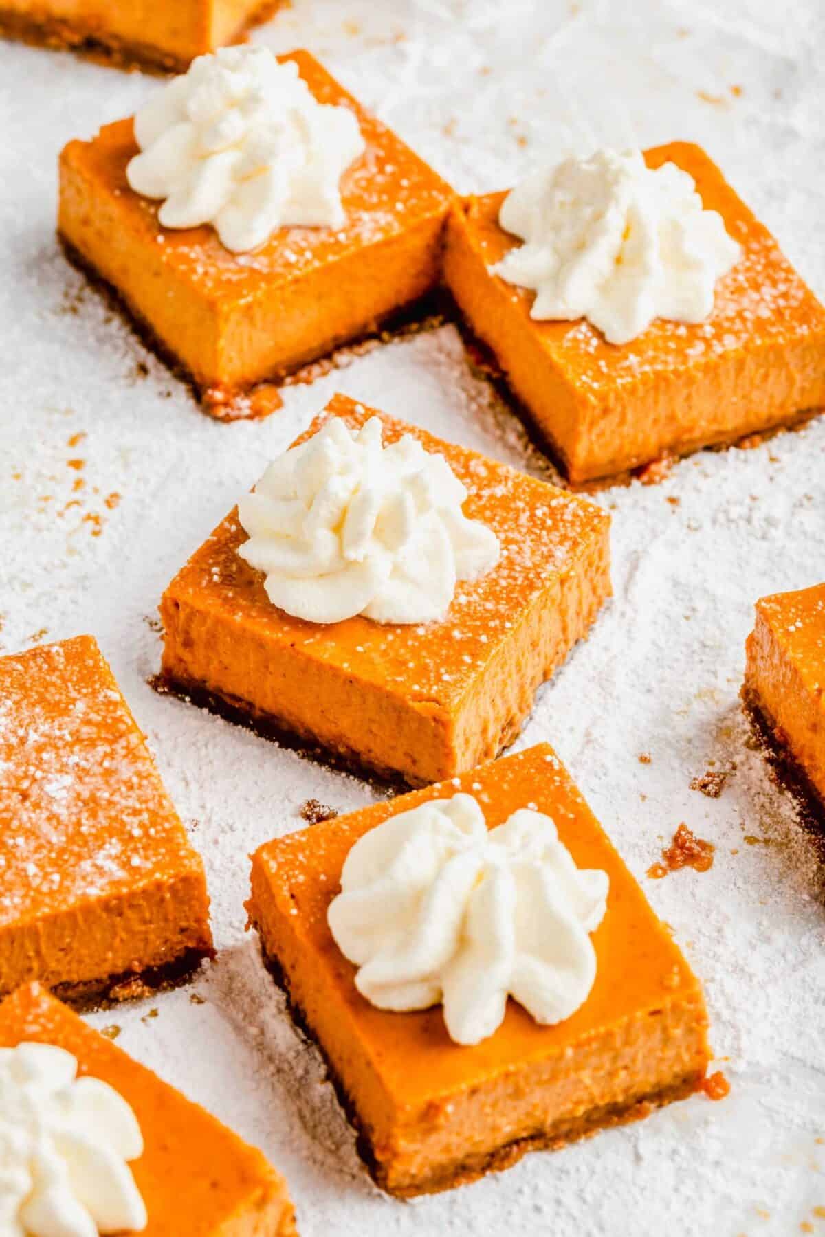 Close up of maple pumpkin cheesecake bars topped with whipped cream