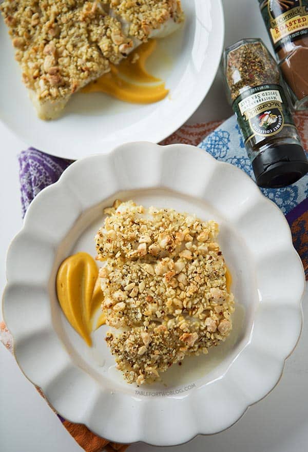 Overhead view of baked almond-crusted halibut fillets on a plates served over a bed of sweet potato puree.