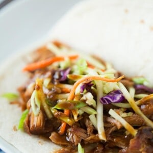 Slow cooker Korean tacos are so easy to make and the results are a tender & flavorful pork wrapped inside a warm tortilla and topped with a tangy slaw!