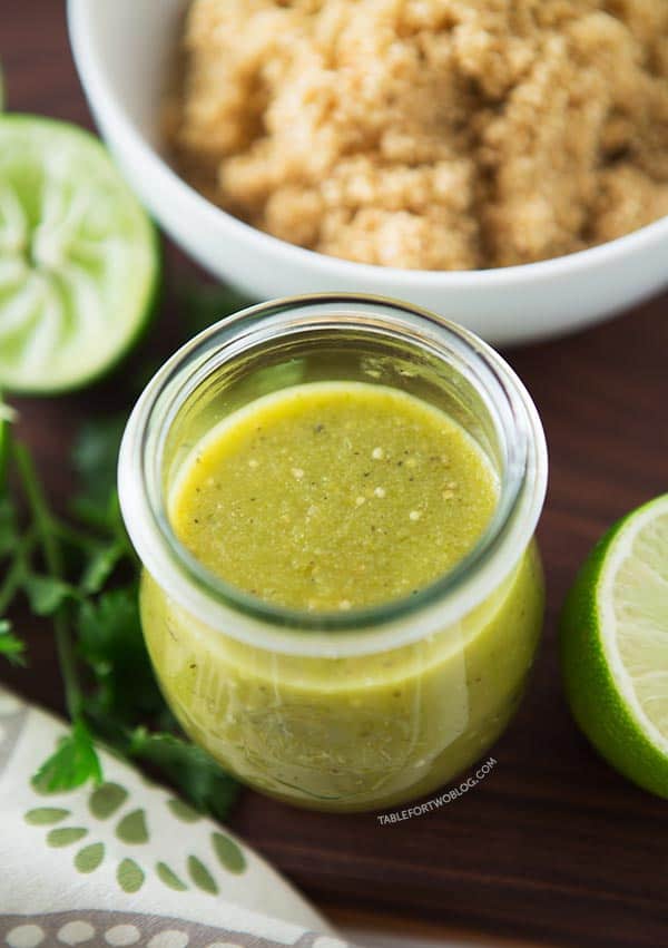 Salsa verde in a jar next to limes and a bowl of quinoa.