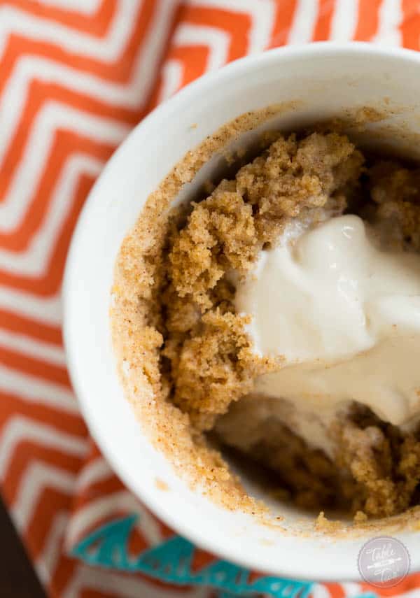 Pumpkin spice mug cake topped with creamy vanilla bean ice cream is Fall perfection...in a mug! Literally! Recipe on tablefortwoblog.com