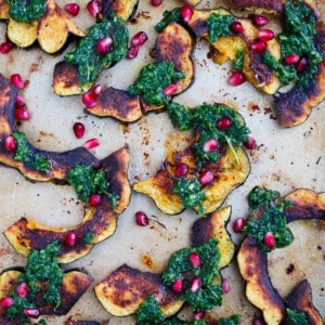 Roasted acorn squash with arugula pesto and pomegranate is a great side dish addition to any meal! You'll love how vibrant and colorful this side dish looks on your table!