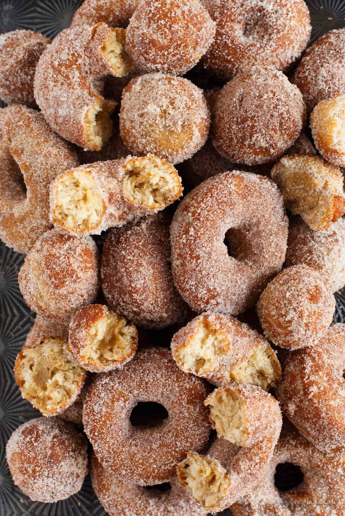 Apple cider doughnuts piled on baking sheet