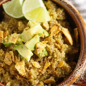 Slow cooker salsa verde pork served in a bowl with a spoon and garnished with avocado and lime.