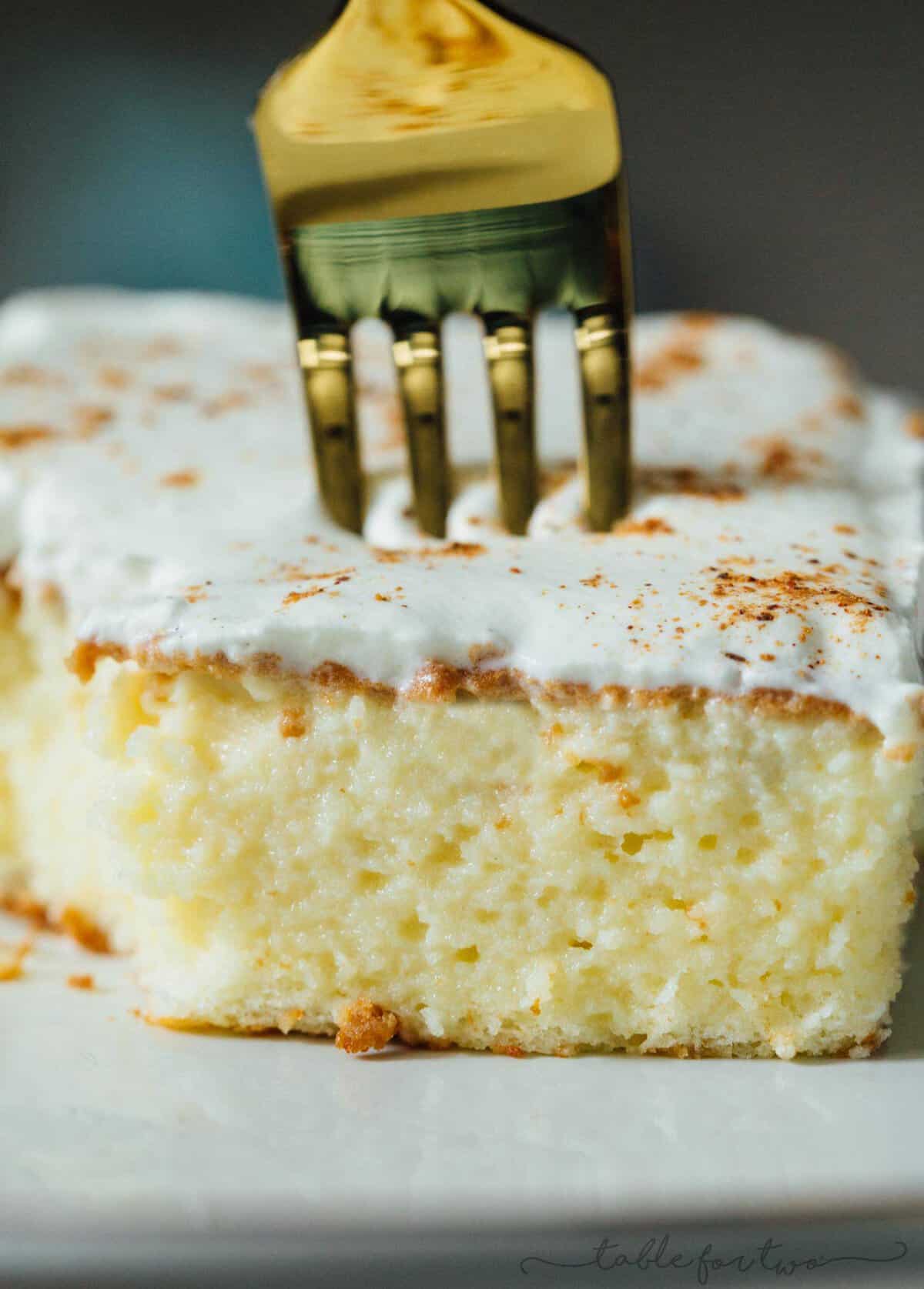 An up close image of the inside of the eggnog tres leches cake with a gold fork piercing the center of it.