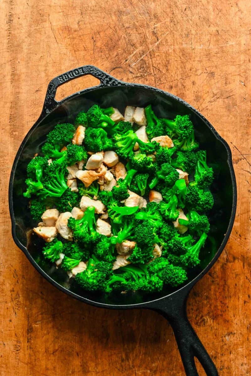 Cubed chicken and broccoli combined in a skillet.