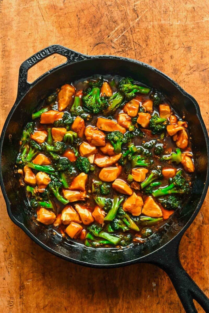Cooked chicken and broccoli tossed with teriyaki sauce in a skillet.