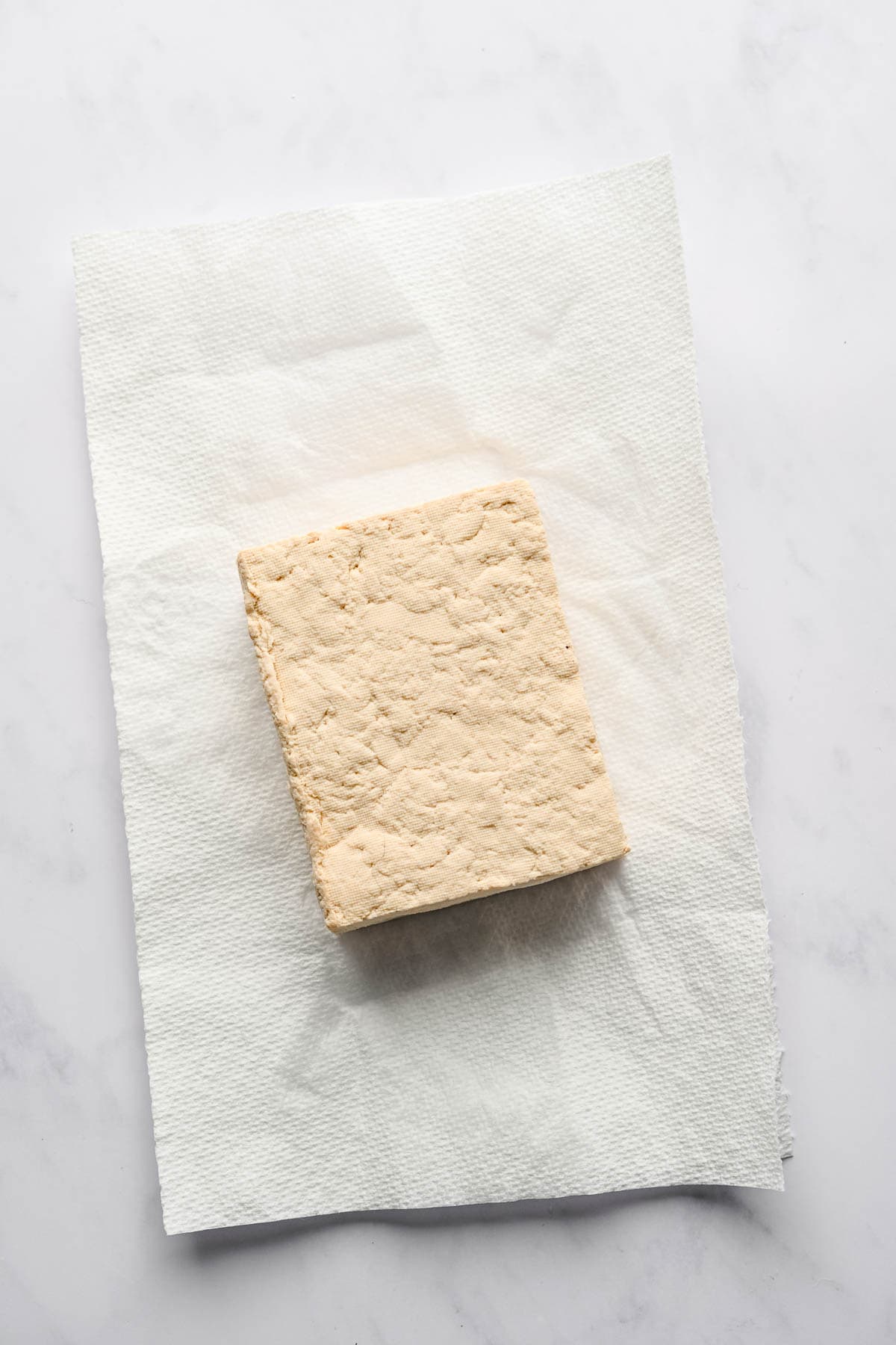 A block of tofu on a piece of paper towel.
