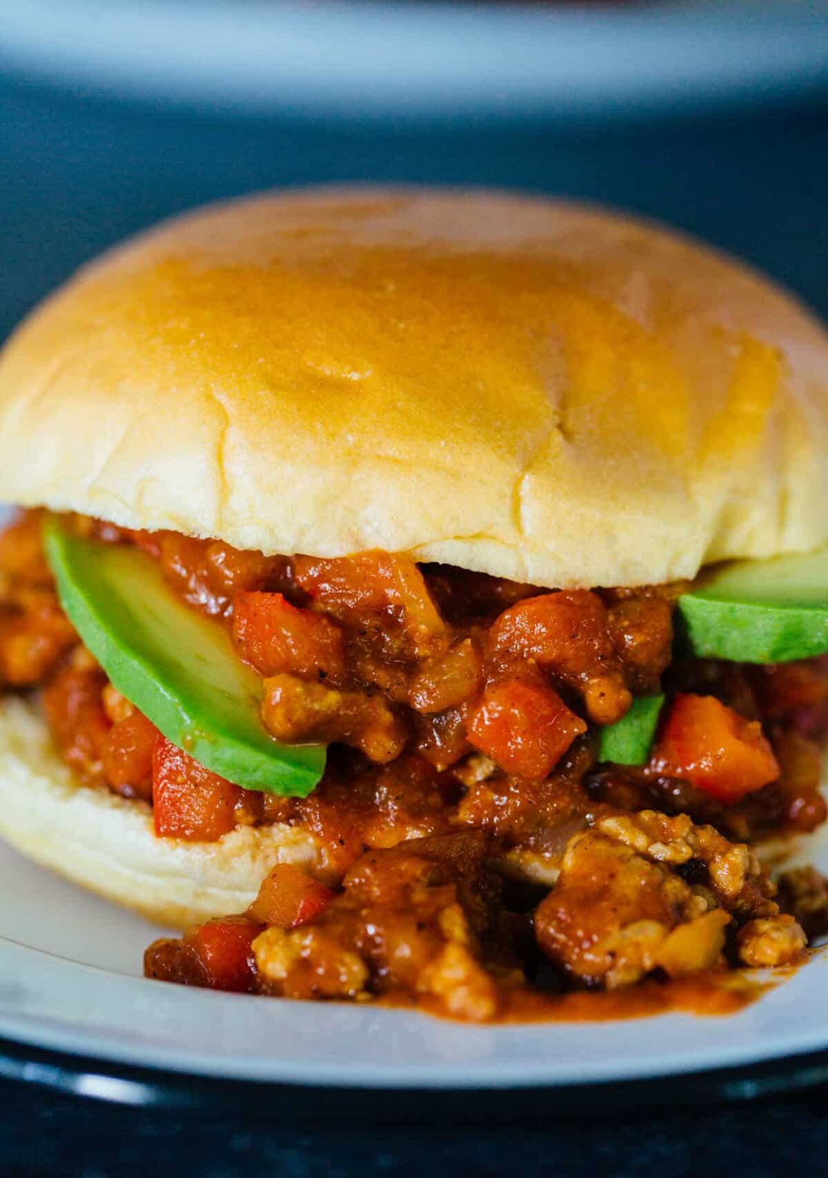 A pumpkin BBQ sloppy joes sandwich spilling out of the bun on a plate.