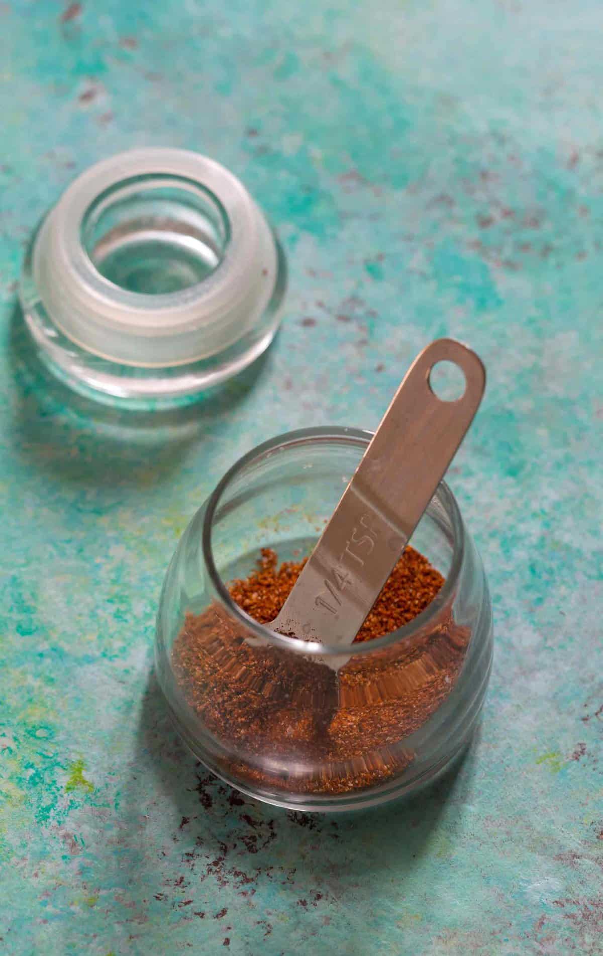 Spoon inside glass jar of fajita seasoning