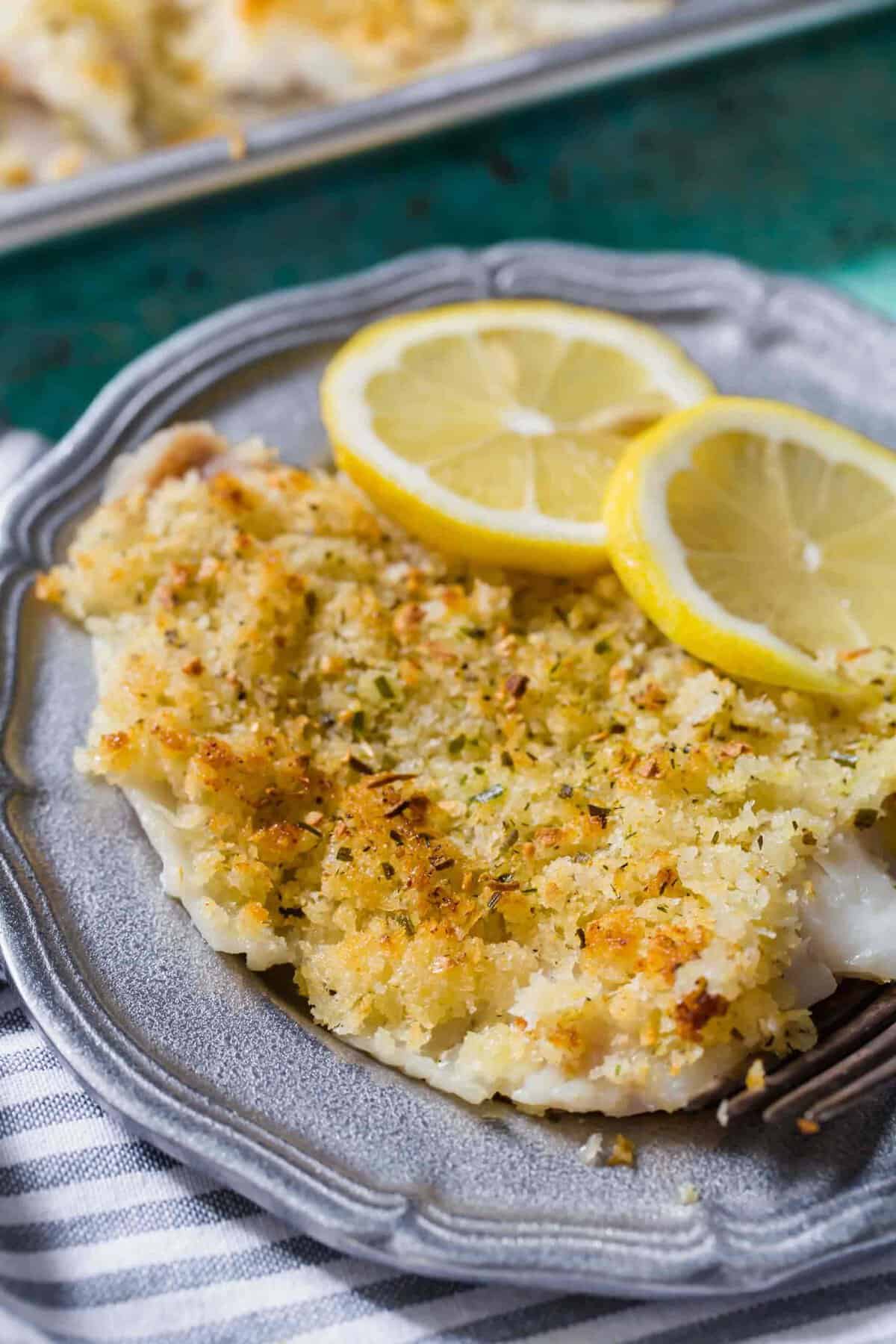 Baked haddock on a plate with lemon slices for garnish