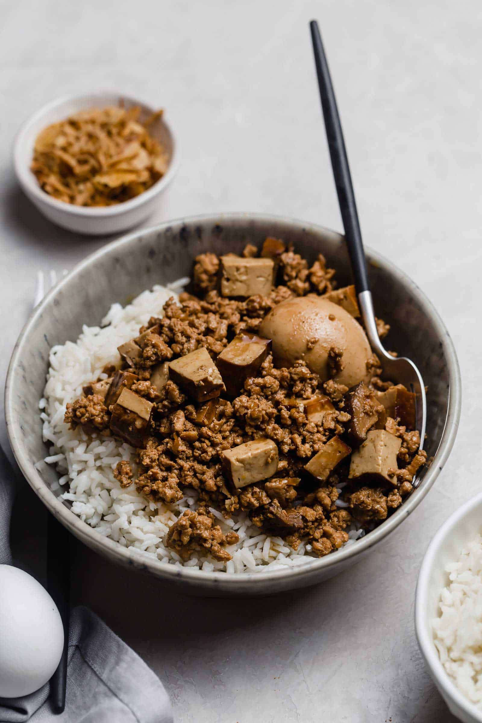 Bowl of rice with ground pork, tofu, an egg, and mushrooms.