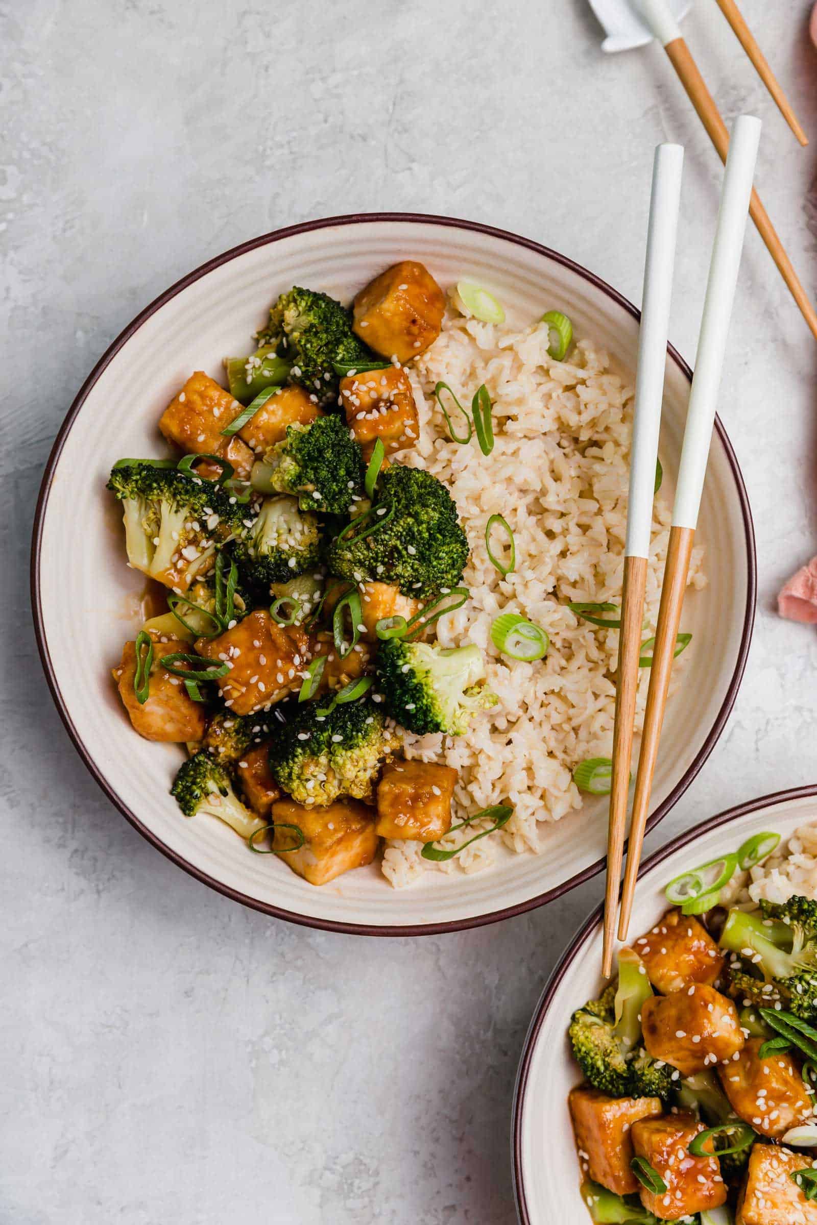 Overhead view of a teriyaki tofu and broccoli bowl with a set of chopsticks.