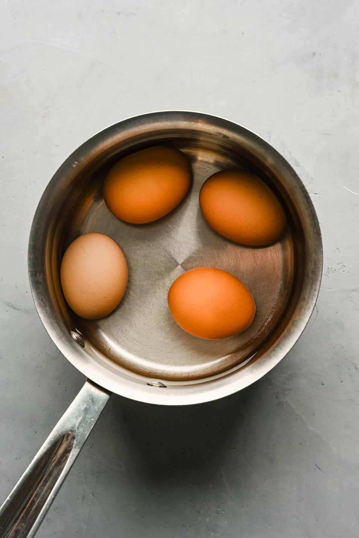 Boiled eggs in a stainless steel saucepan.