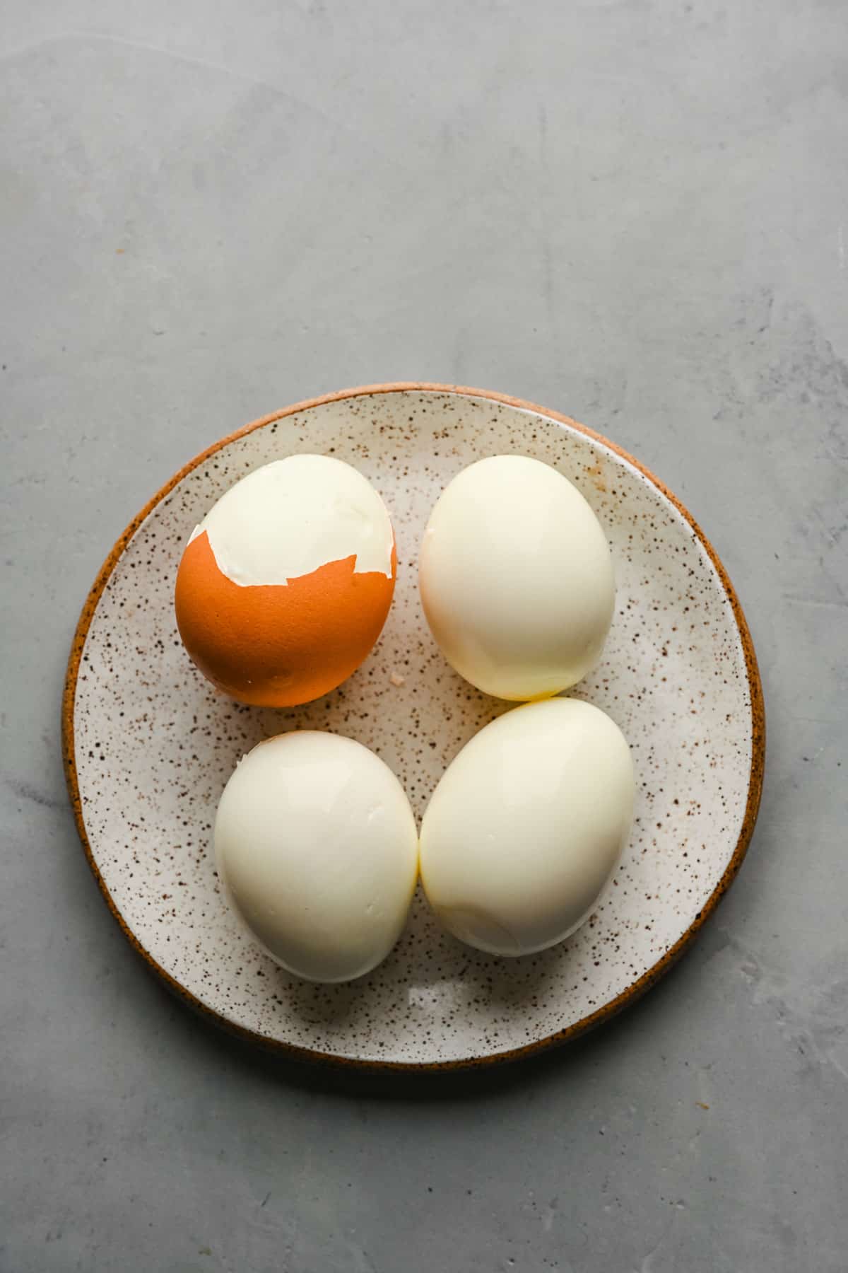 Partially peeled hard boiled eggs on a plate.