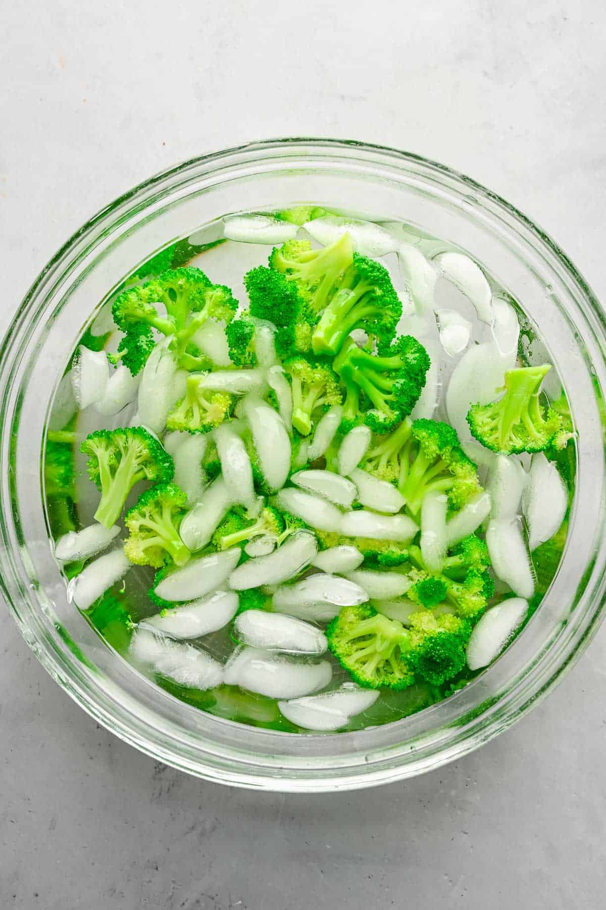 Blanched broccoli in a bowl of ice water.