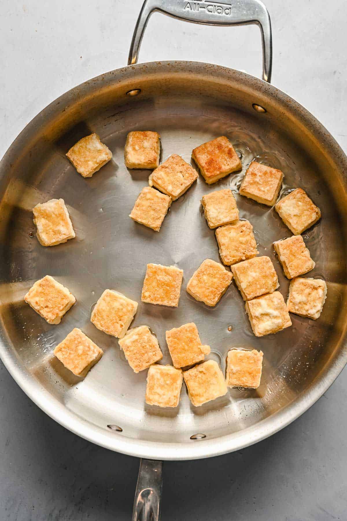 Browned cubed tofu in a metal skillet.