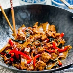 Drunken noodles with tofu in wok with chopsticks.