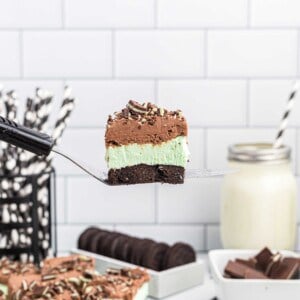 a slice of andes mint cheesecake is lifted in the air with a metal spatula to show the 3 distinct layers