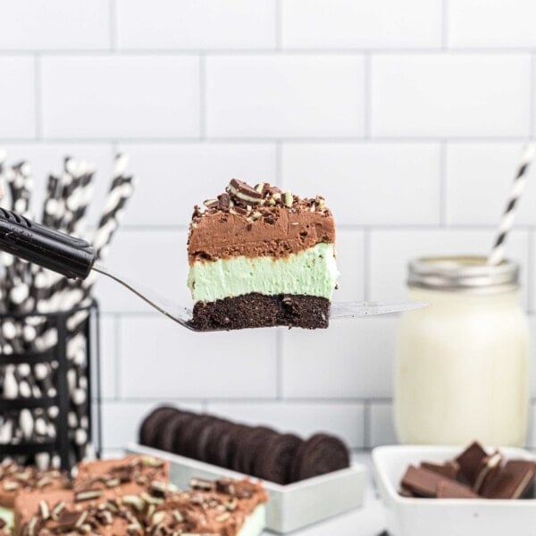 a slice of andes mint cheesecake is lifted in the air with a metal spatula to show the 3 distinct layers