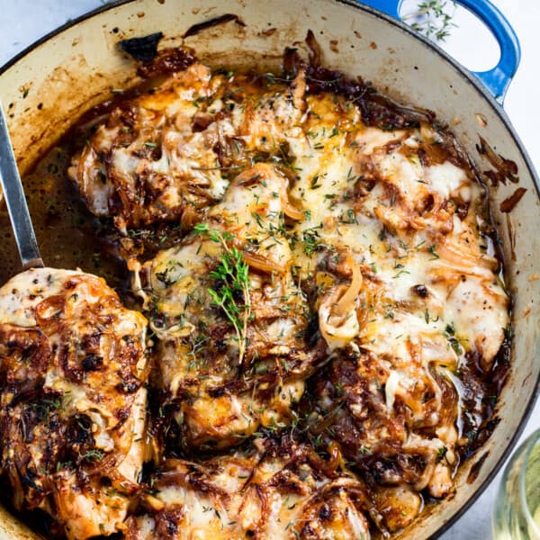 french onion chicken in a dutch oven with fresh thyme leaves and melted cheese on top
