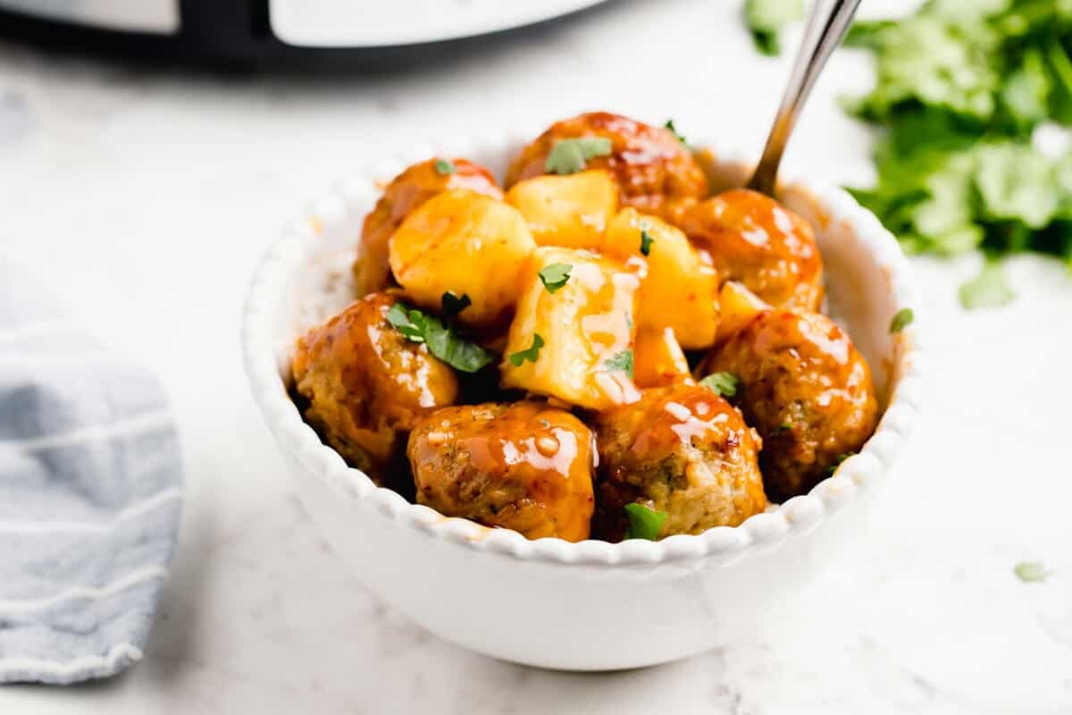 a small white bowl containing sweet and sour meatballs