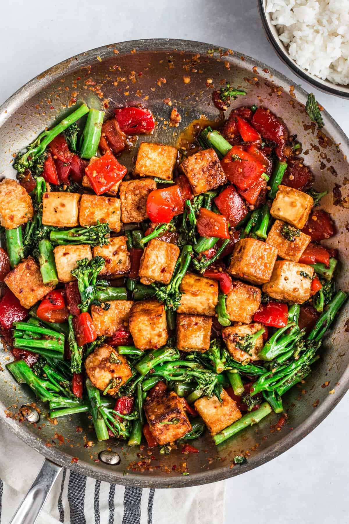 Spicy chili tofu stir fry is being cooked in a large skillet.
