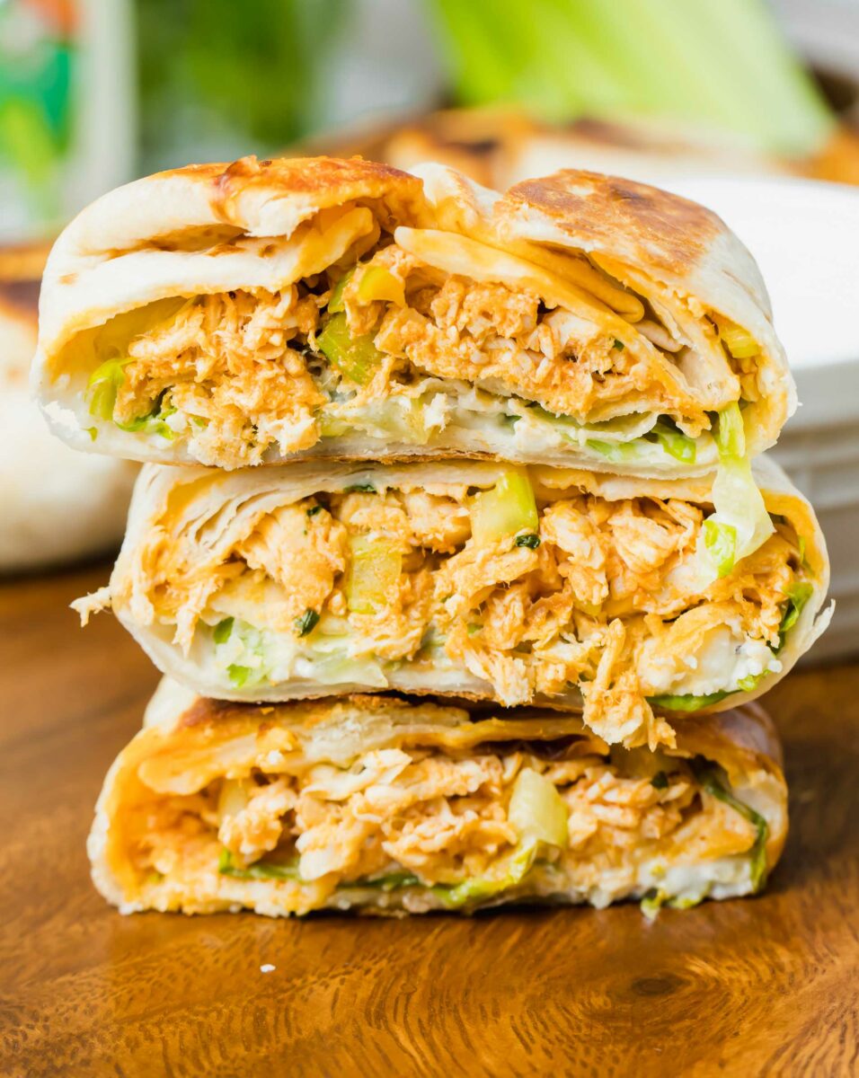 Three mini buffalo chicken appetizers have been cut in half and stacked in a little pile. 