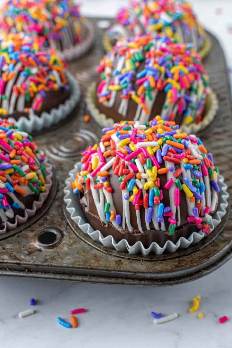 A close up shot shows the rainbows sprinkles and white drizzle on the hot cocoa bomb.