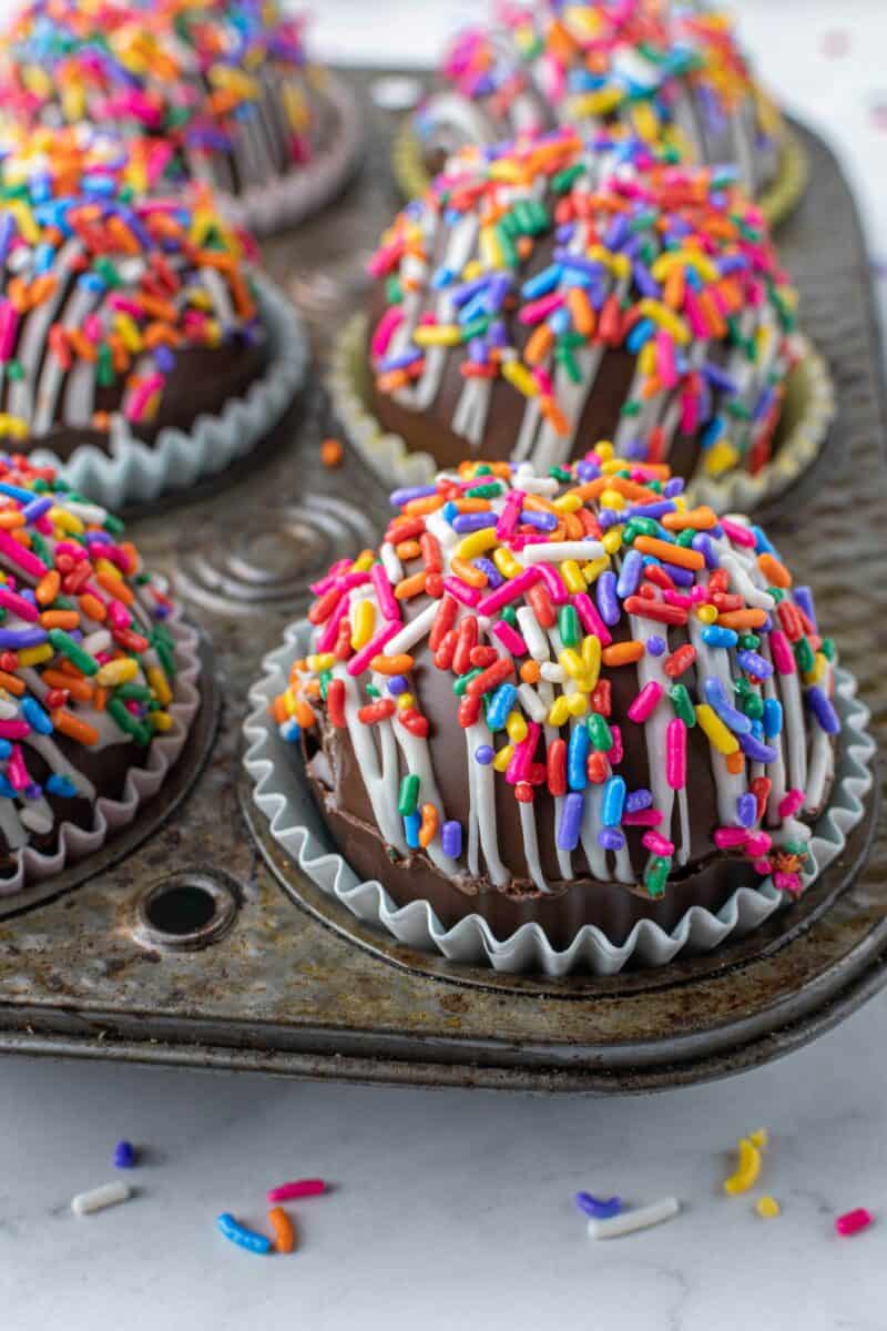 A close up shot shows the rainbows sprinkles and white drizzle on the hot cocoa bomb.