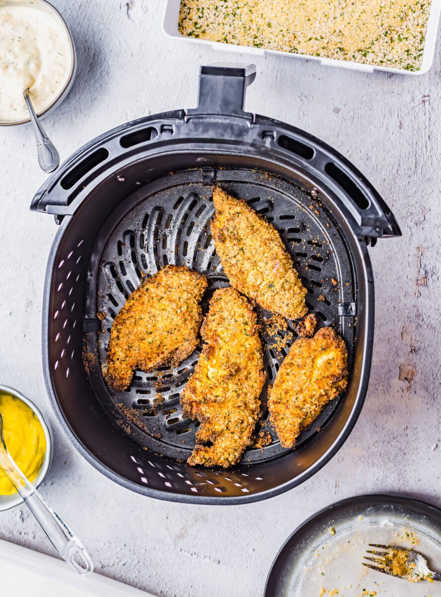 Four pieces of catfish cooked are in the air fryer basket.