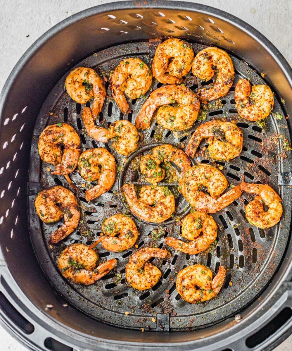 Shrimp are placed on the bottom of an air fryer basket. 