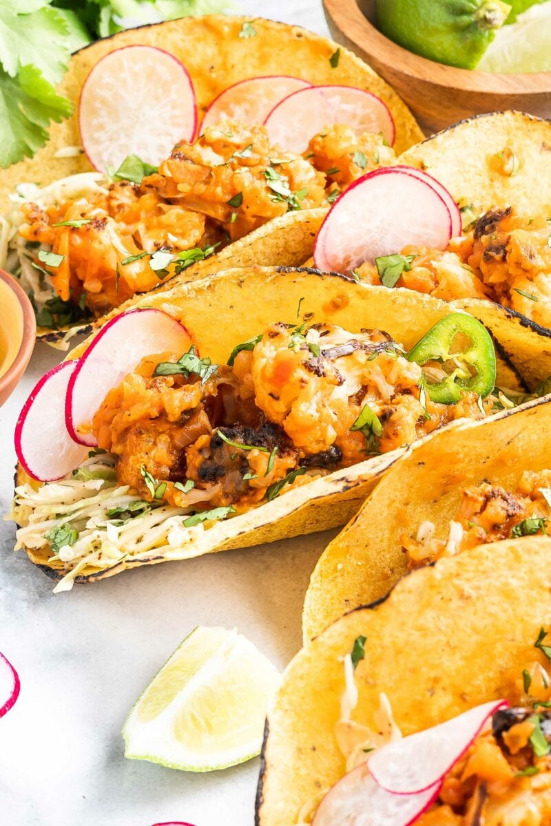 Cauliflower tacos are garnished with sliced radishes and jalapeños. 