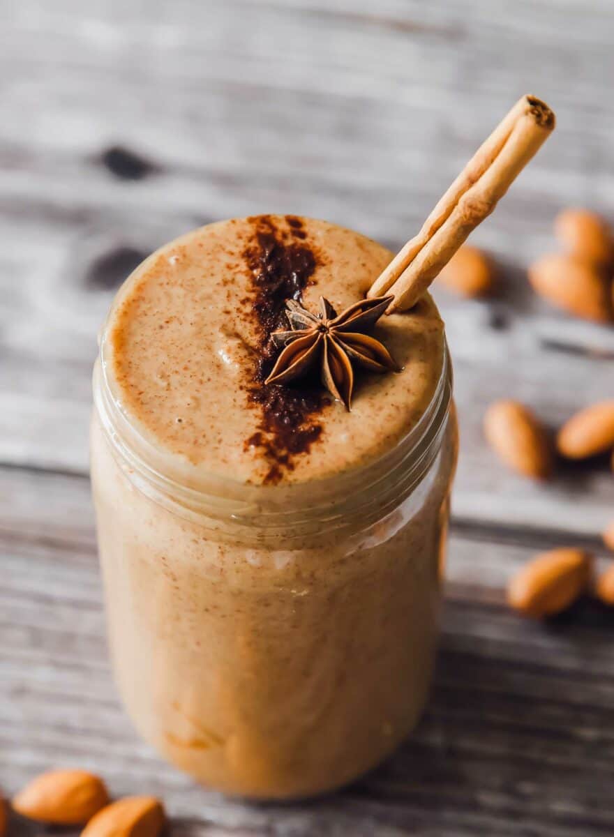 A close up shot shows the details of the brown, cinnamon sprinkled almond butter in a glass mason jar. 