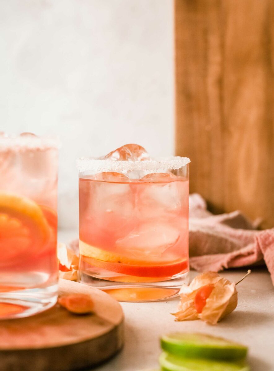 A glass of citrus rosé sangria is rimmed with sugar and filled with ice cubes.