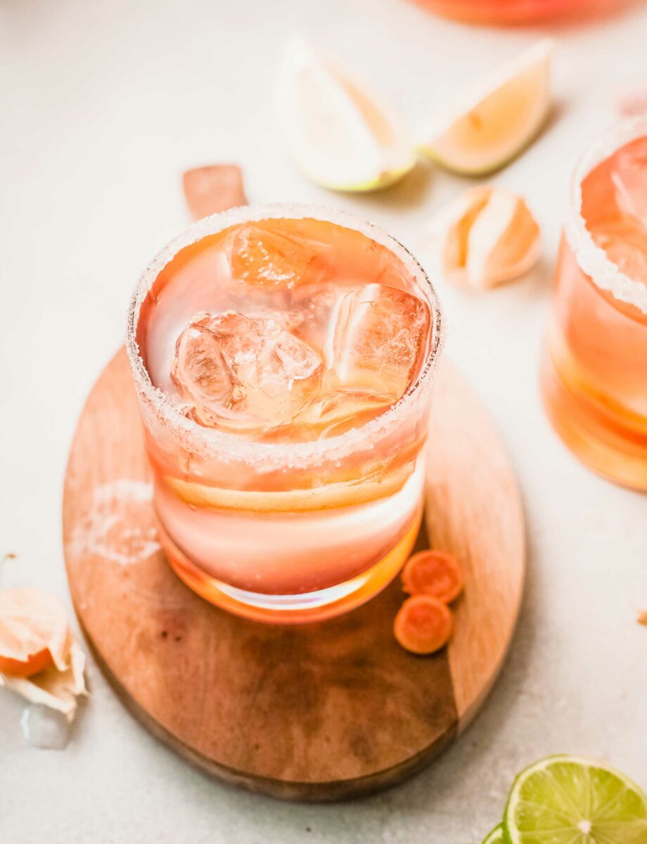 A glass of citrus rosé sangria is placed on a wooden surface. 