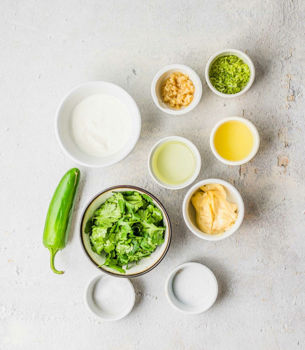 The ingredients for creamy cilantro dressing are placed on a white surface. 