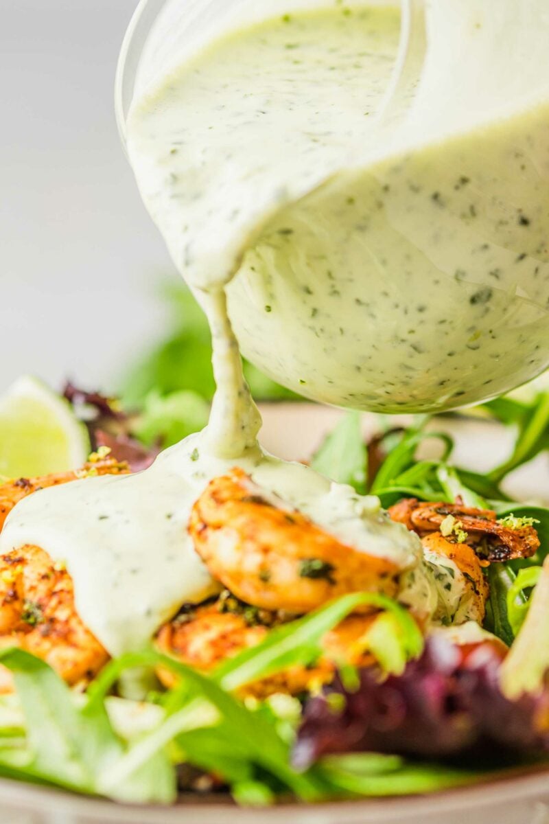 Dressing is being drizzled onto a shrimp salad. 