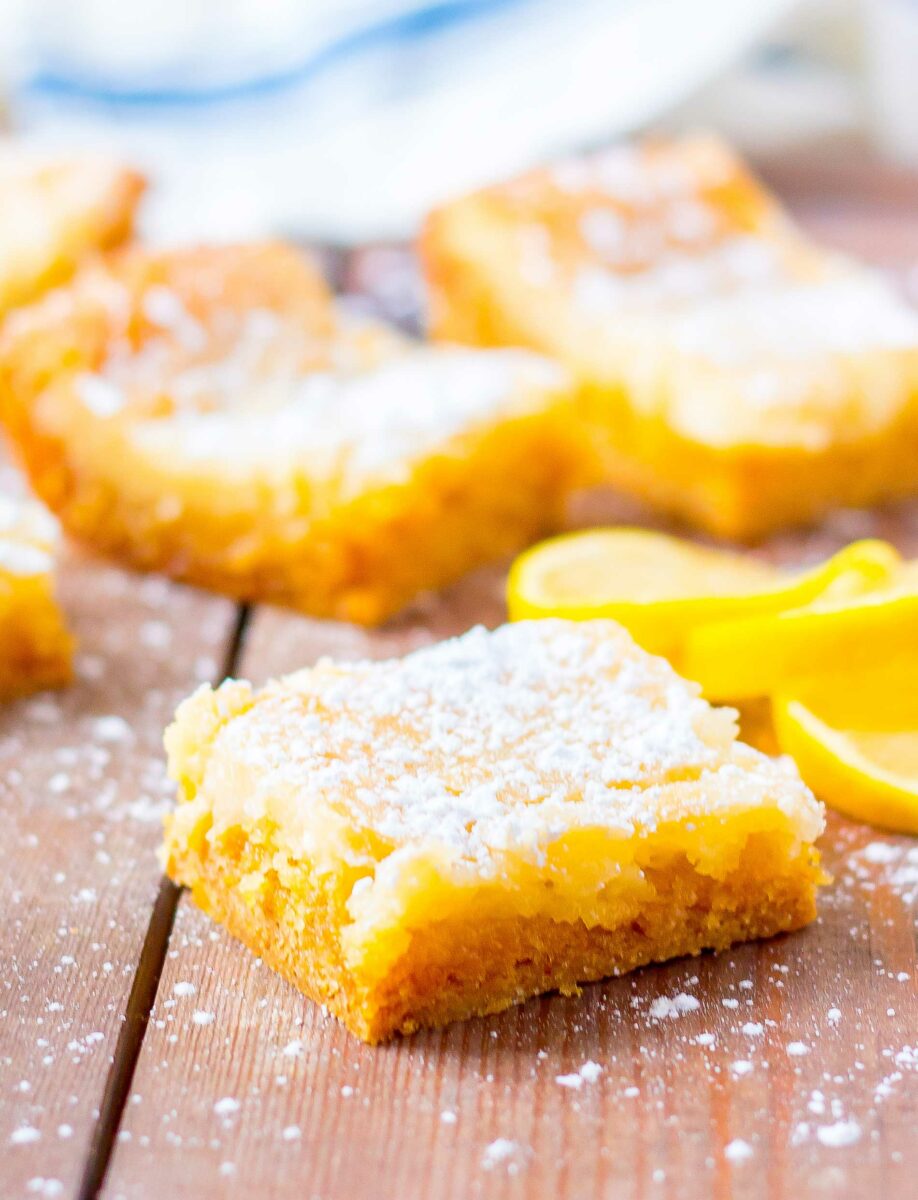 A few slices of lemon are placed next to a piece of gooey lemon cake. 