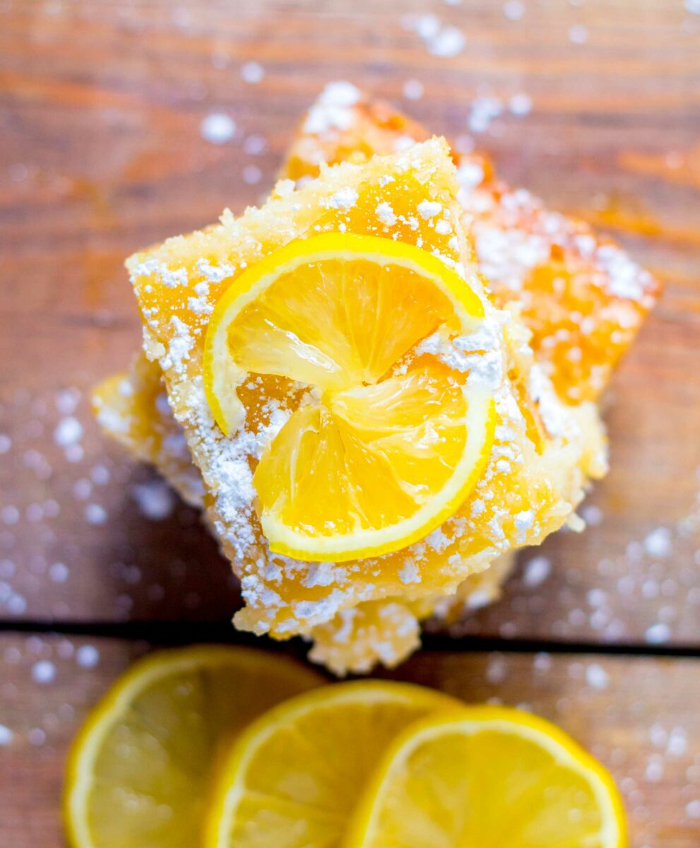 Lemon slices and cake pieces are placed on top of a wooden surface. 