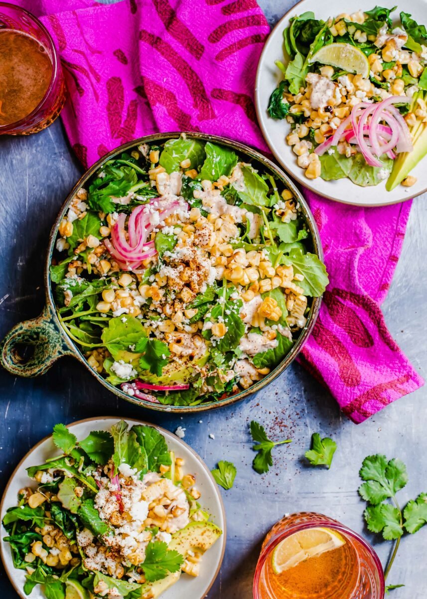 A large bowl filled with salad is placed next to two small plates. 