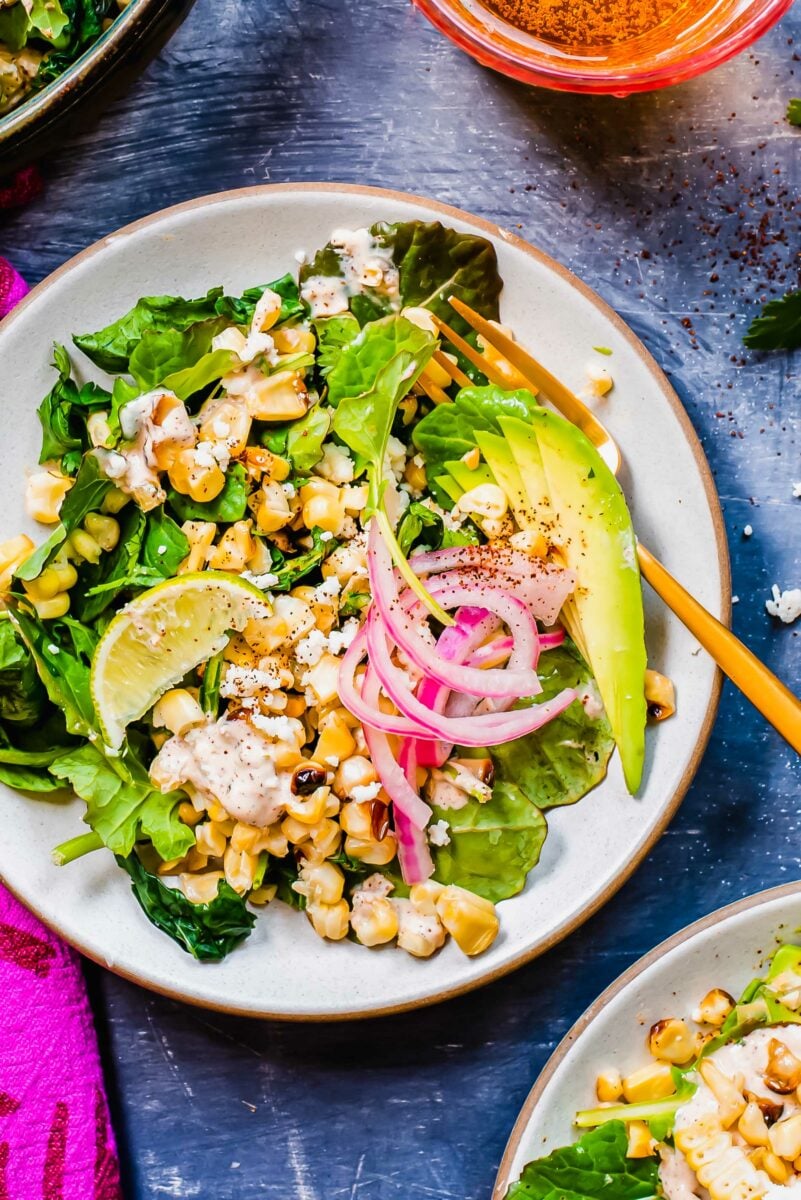 Sliced avocado and lime garnishes a corn salad. 