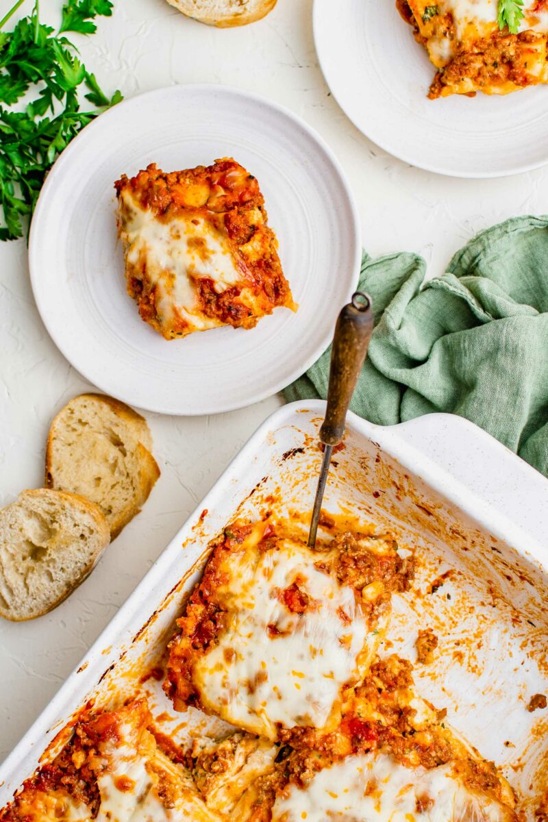 A white baking dish is full of cut lasagna squares.